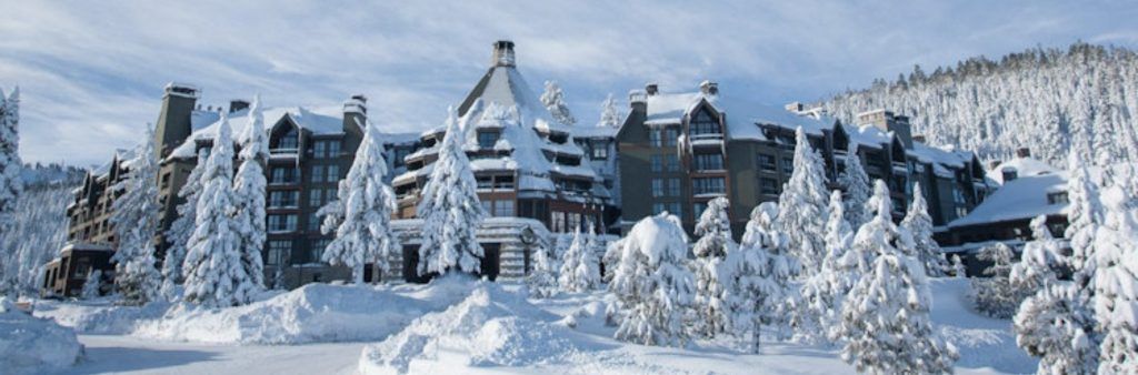 The Ritz-Carlton resort in Lake Tahoe surrounded by snow-covered pine trees in a mountain setting.