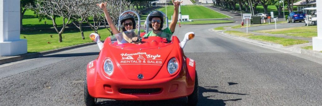 Couple riding a red Scoot Coupe on a sunny road in Hawaii.