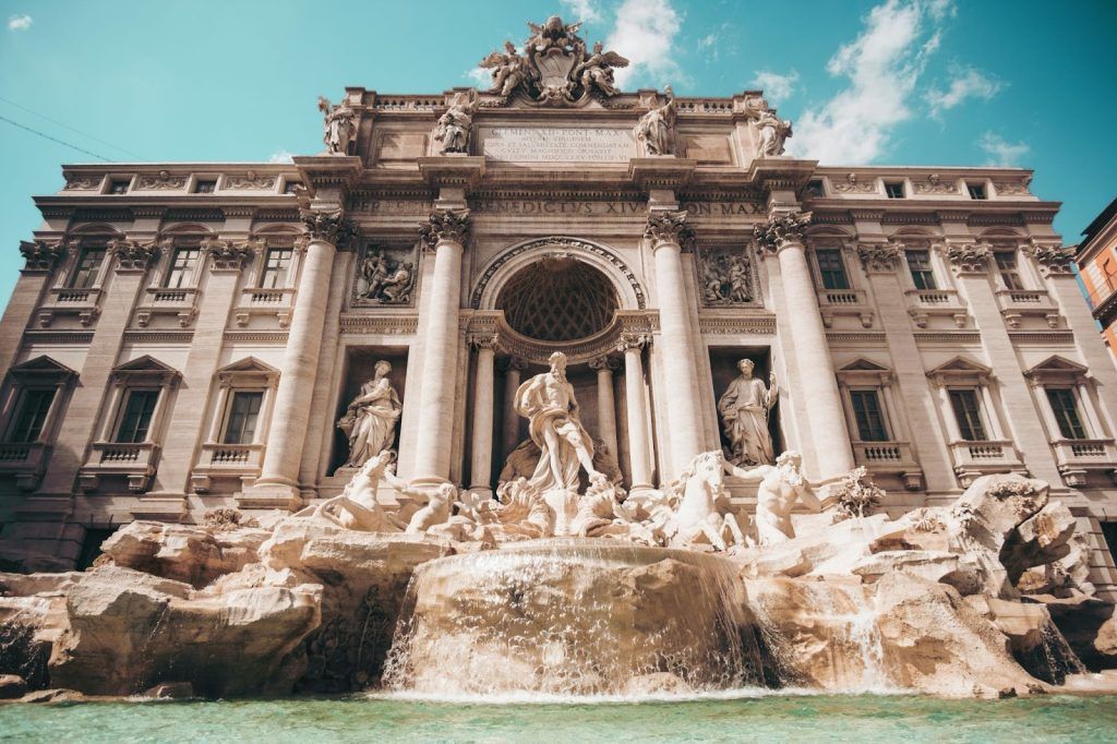The Trevi Fountain in Rome with detailed statues and cascading water under a bright sky.