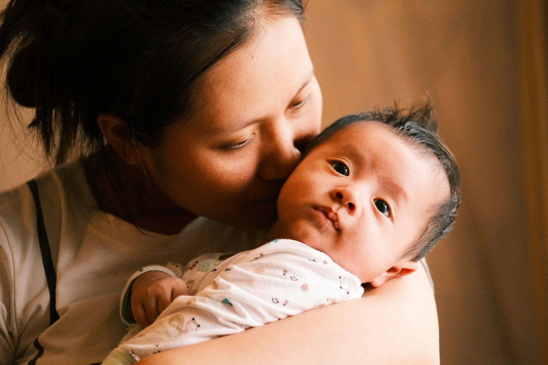 Mother kissing her baby while holding them close.